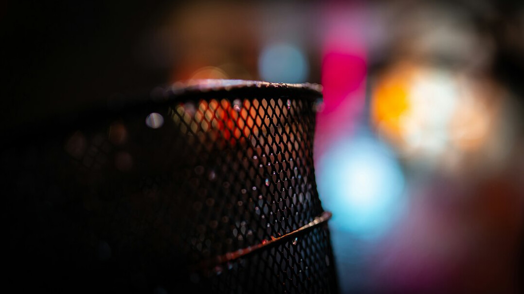 Close up of a professional podcast microphone with a pop filter in a warm lit studio